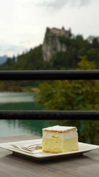 Bled cream cake on a cafe plate with Bled Castle softly blurred behind, vertical parallax move