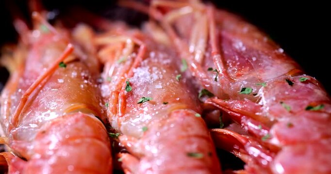 Close up of delicious prawns cooking with garlic and parsley. Hot pan with oil and seafood creating steam and golden texture.