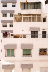 urban facade in a city centre of Morocco featuring a white wall with tilted windows.