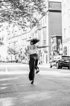 Woman dancing freely on urban city street in motion
