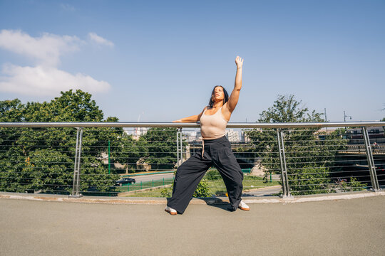 Woman dancing freestyle on urban bridge expressing freedom