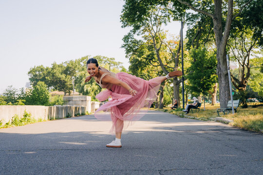 Woman dancer balancing in pink tulle skirt in park