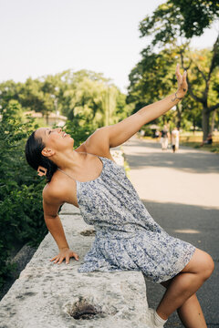 Woman smiling reaching sunlight in urban park