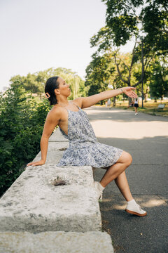 Woman posing in park balancing on stone wall