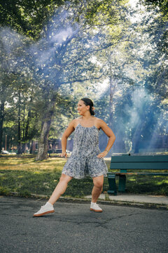 Woman enjoying summer day dancing in park with smoke