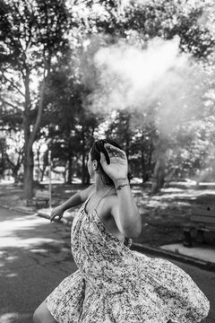 Woman dancing with smoke cloud in park