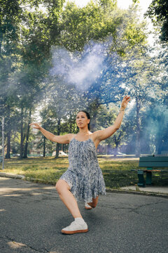 Woman performing contemporary dance with blue smoke outdoors