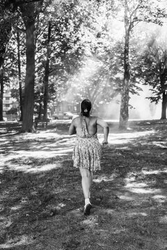 Woman running in park with sunlight and trees