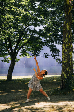 Woman performing expressive contemporary dance in park with smoke