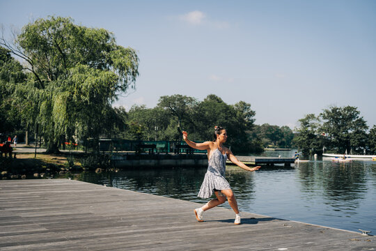 Woman dancing on dock by lake enjoying summer