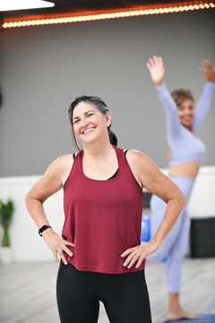 Smiling woman posing confidently in fitness studio after workout