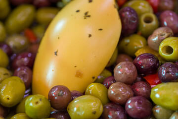 Fresh mixed olives on display at deli counter in a busy rotisserie shop for takeaway