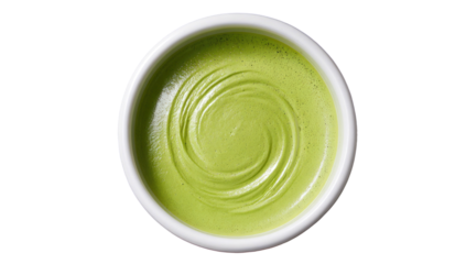 Overhead view of a creamy green liquid in a white bowl against a black background
