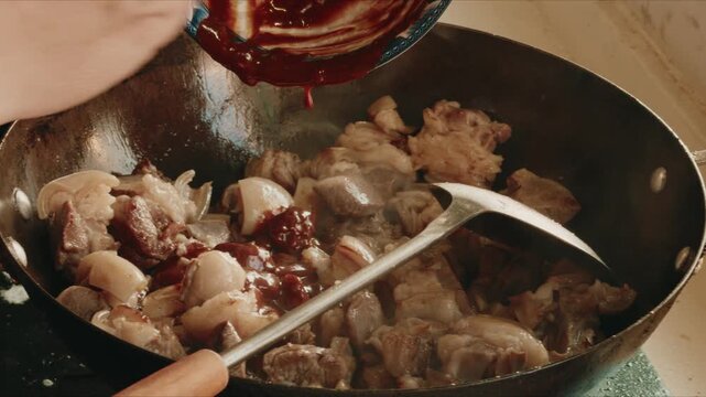 A chef is frying dry pot lamb in an iron pan