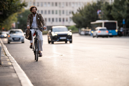Businessman riding bicycle in city traffic during commute