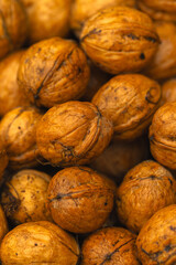 walnuts and kernels captured in a rustic natural setting. Some nuts are cracked open, revealing the rich interior texture, while others remain whole on a dark wooden surface. 

