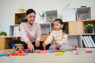 toddler girl and mother playing colorful magnetic construction toy at home