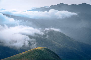 A man with his tent is taking a view of Mountain Range view point in Myanmar (Burma) with sea of cloud (Mulayit Taung) and sunrise