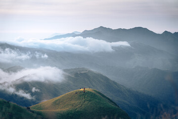 A man with his tent is taking a view of Mountain Range view point in Myanmar (Burma) with sea of cloud (Mulayit Taung) and sunrise