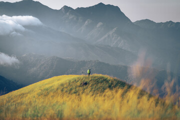 A man with his tent is taking a view of Mountain Range view point in Myanmar (Burma) with sea of cloud (Mulayit Taung) and sunrise