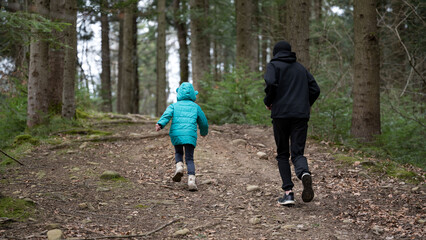 Exploring the tranquil forest trail together under the soft glow of the afternoon sun, a child and...