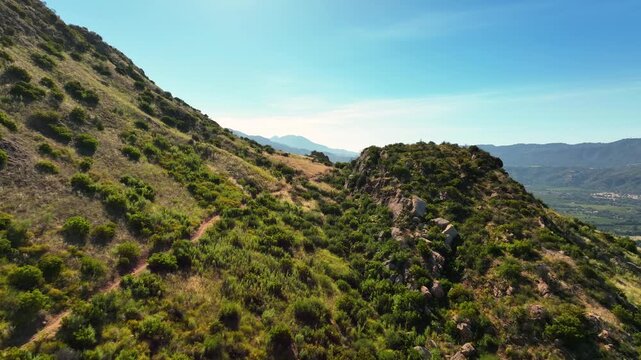 Low altitude flight over a rugged mountain to reveal the Ojai Valley and its famous organic farms - forward aerial reveal