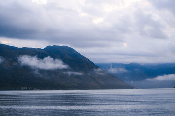 Dramatic mist rolling over mountain landscape by bay