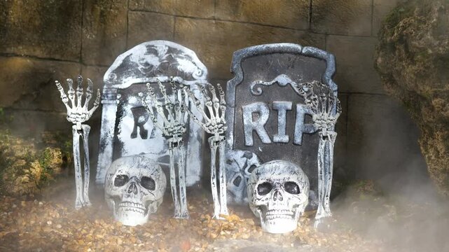 Multiple skulls and skeleton hands rising from graves with RIP tombstones and fog, spooky Halloween cemetery decoration for horror festival theme