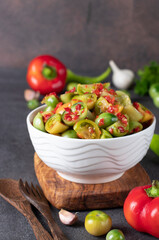 Salad of green tomatoes with hot peppers and garlic in white salad bowl