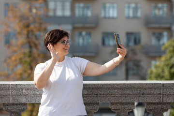 A middle-aged woman records videos on her phone, blogger, video call