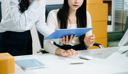 Asian team woman on desk in office of fashion designer and holds tablet, laptop and smartphone on white table