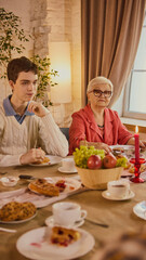 Elderly woman in glasses sharing meal with grandson at table. Concept of emotional closeness, intergenerational support, social campaigns, psychology, and well-being.