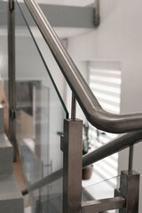 A stylish staircase showcases sleek stainless steel handrails and glass panels. The modern design complements the light-filled space, enhancing overall aesthetics and functionality
