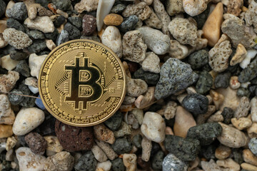 Golden Bitcoin Cryptocurrency Coin on Pebble Stone Background