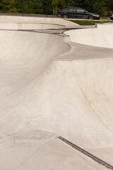 The skatepark features smooth concrete curves and ramps, inviting skaters to practice tricks. A...