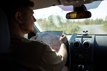 A man in a car is studying a road map