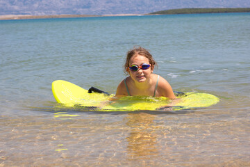 Girl floating on a boogie board in clear water