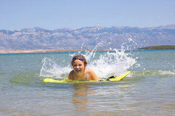 Girl swimming with boogie board at the beach