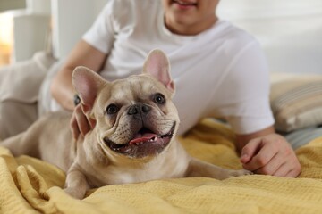 Man with his cute French bulldog on bed at home, closeup