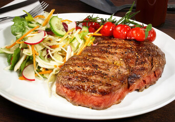 Medium Beef Steak from Grill with mixed Lettuce and grilled Cherry Tomatoes