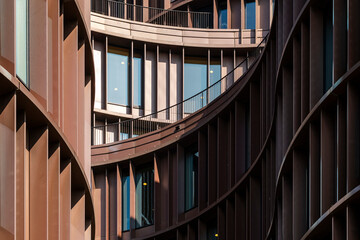 Modern curved facade architecture in Copenhagen with bronze tones and rhythmic vertical lines creating elegant visual flow and soft light reflections enhancing urban design aesthetic