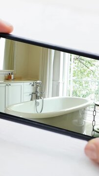 Person holding smartphone with modern bathroom interiors displayed on screen