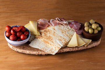 Pane carasau con salame, formaggio e olive su un vassoio di sughero 