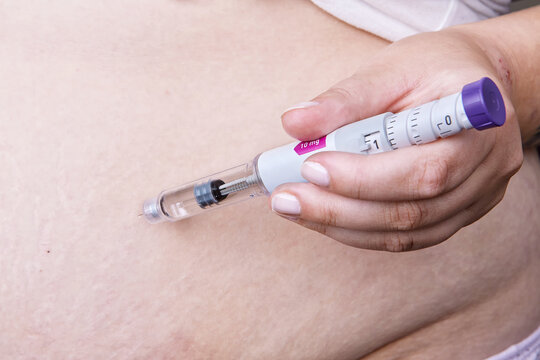 Weight loss and diabetes treatment. Person using Mounjaro insulin injector pen or GLP-1 injection for shot in abdomen. Obesity therapy, hormonal medication, semaglutide injection, modern healthcare	