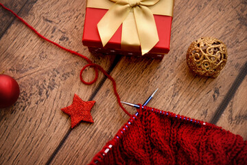 Christmas decoration and red knitting on wooden background