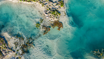 Top down aerial photograph of a crystal clear water body its shallow parts revealing the textured sand bed below surrounded by a unique mineral shoreline a study in natural clarity