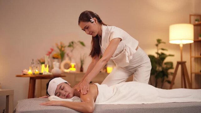 Asian adult women receive relaxing body oil massage from masseuse in serene tranquil spa environment for ultimate rejuvenation wellness treatment