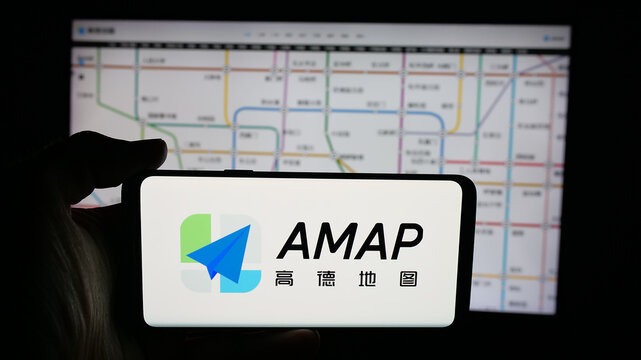 Stuttgart, Germany - 10-13-2025: Person holding cellphone with logo of Chinese online map service company AMap on screen in front of webpage. Focus on phone display.