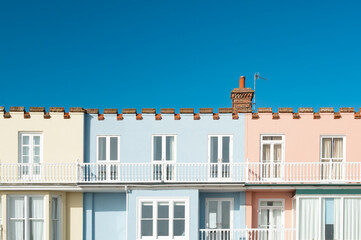 Wonderful pastel coloured first floor holiday apartments and balconies seen in bright sun. Located on the Suffolk, UK coastline. They are rented as holiday lets in the summer.