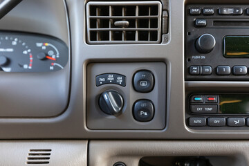 Central dashboard controls of a 2004 American 4x4 family SUV showing 2WD and 4WD selector switch, rear defrost, and parking assist buttons integrated in beige panel interior design detail